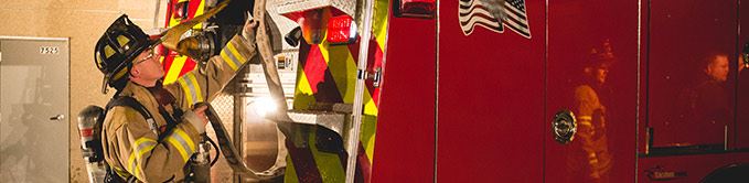 Firefighter Grabbing Hose From Back of Red Fire Truck